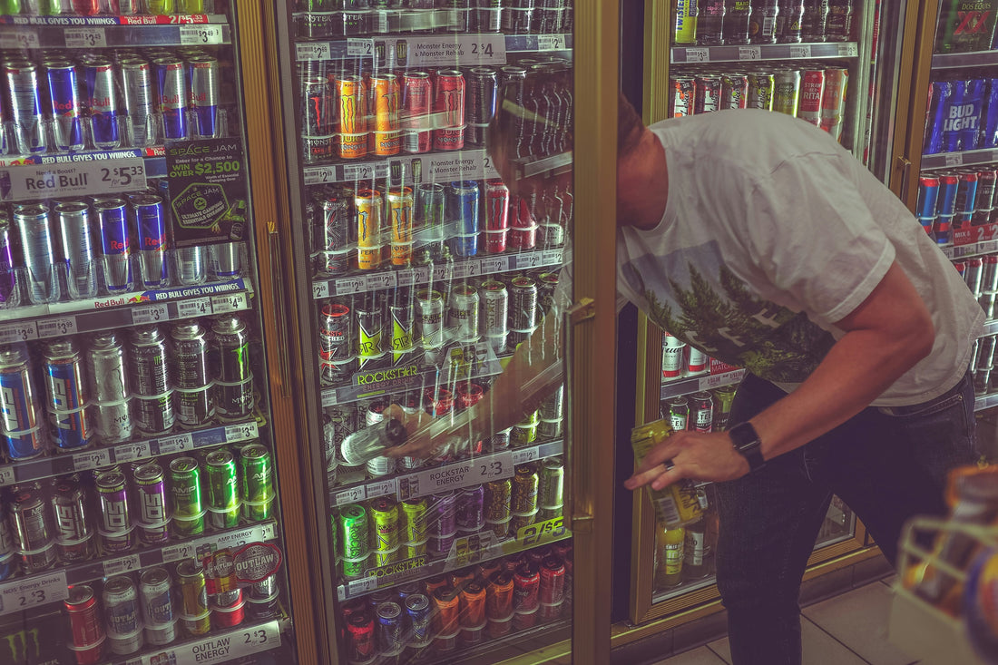 man selecting an energy drink from a refrigerator