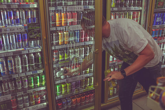 man selecting an energy drink from a refrigerator