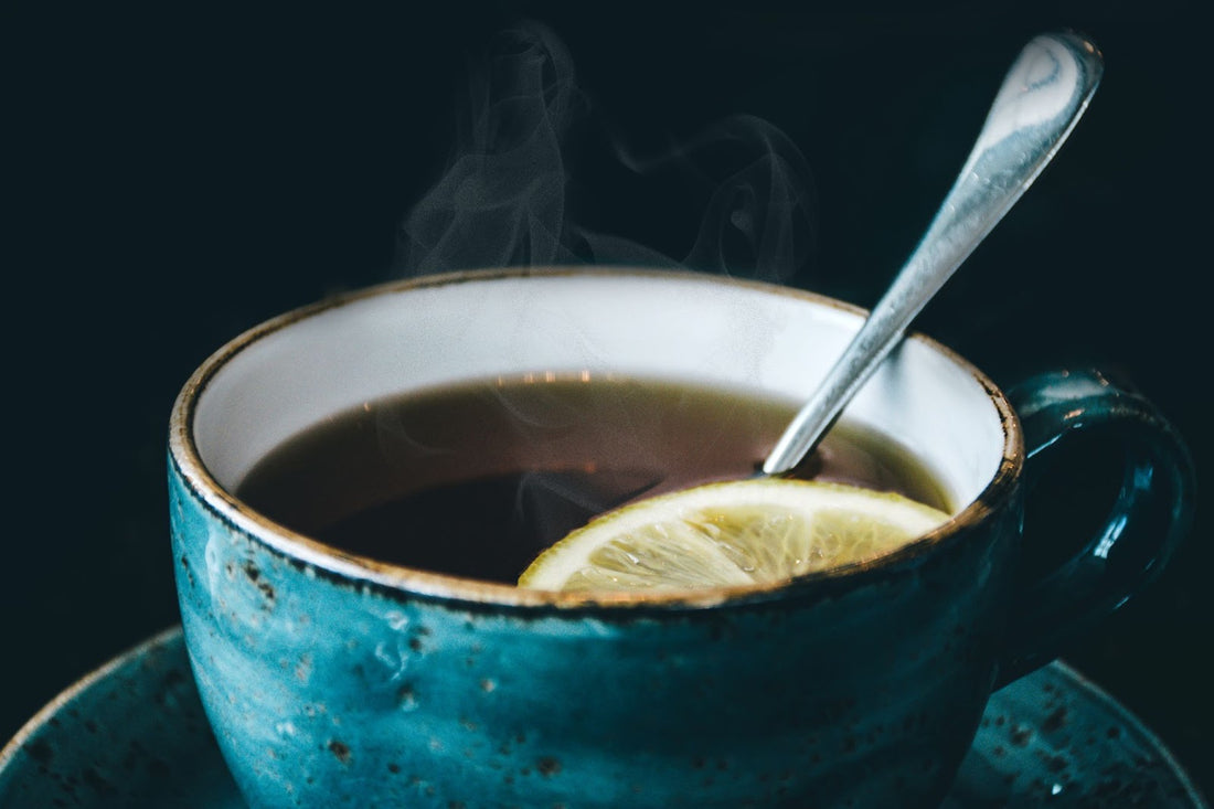 Blue cup filled with tea, a spoon, and a slice of lemon