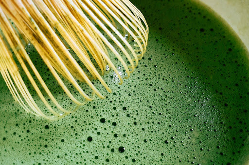 Matcha being whisked with a bambo whisk