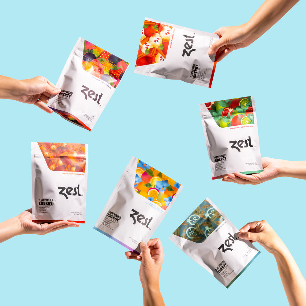 Six hands holding Zest Tea pouches in all flavors arranged in circle on blue background
