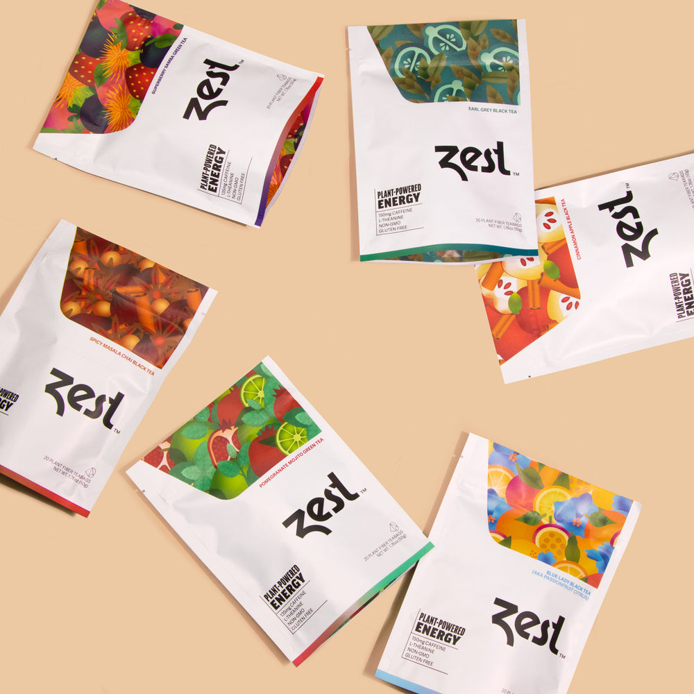 Six Zest Tea pouches scattered on peach background showing all flavor varieties