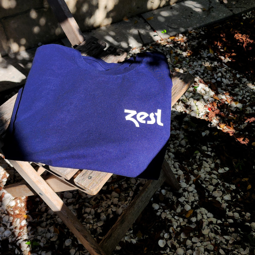 Folded navy Zest t-shirt on wooden chair outdoors in sunlight