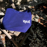 Folded navy Zest t-shirt on wooden chair outdoors in sunlight