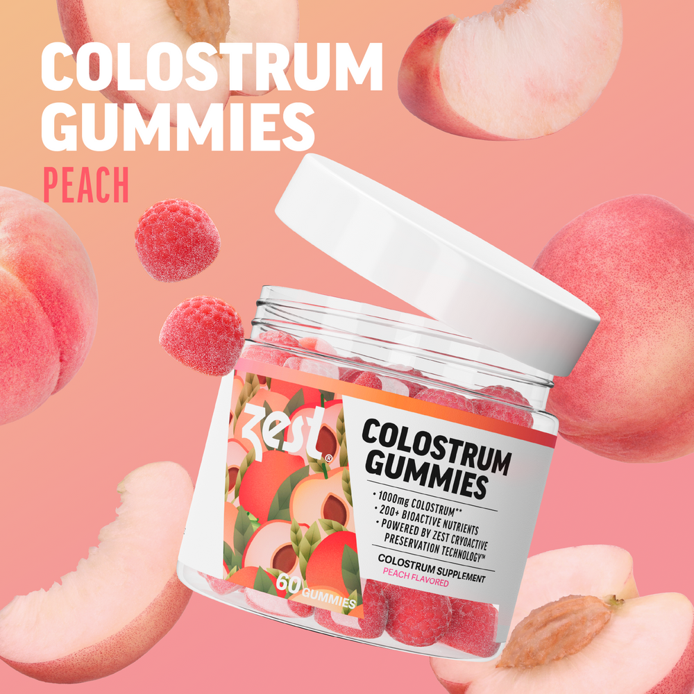Zest Colostrum Gummies jar open with peach gummies on pink background