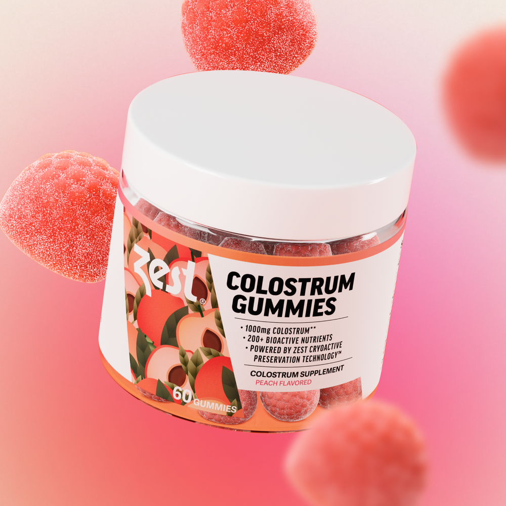 Zest Colostrum Gummies jar with gummies floating on pink gradient background