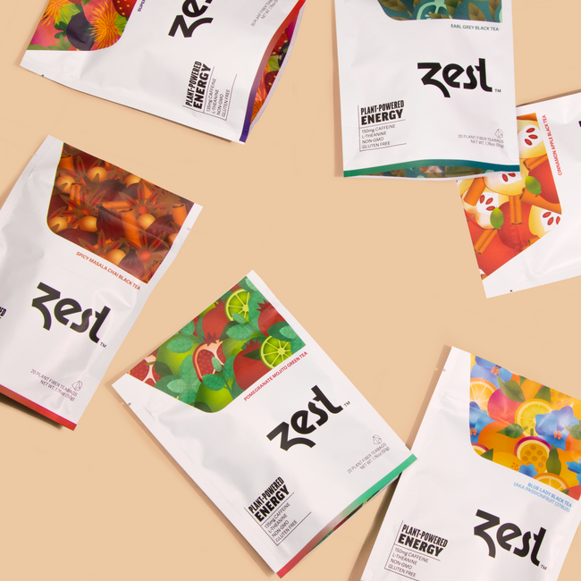Six Zest tea pouches arranged in flat lay on beige background