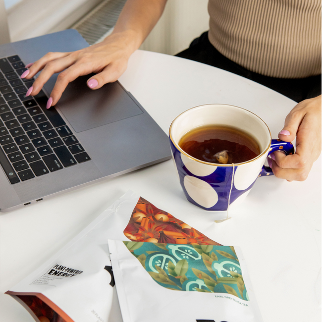 Woman relaxing on couch with laptop and cup of Zest tea