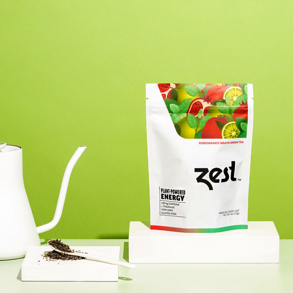 Zest Pomegranate Mojito Loose Leaf pouch with gooseneck kettle and loose tea on green background