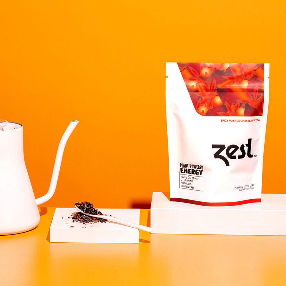 Zest Spicy Masala Chai Loose Leaf pouch with gooseneck kettle and loose tea on orange background