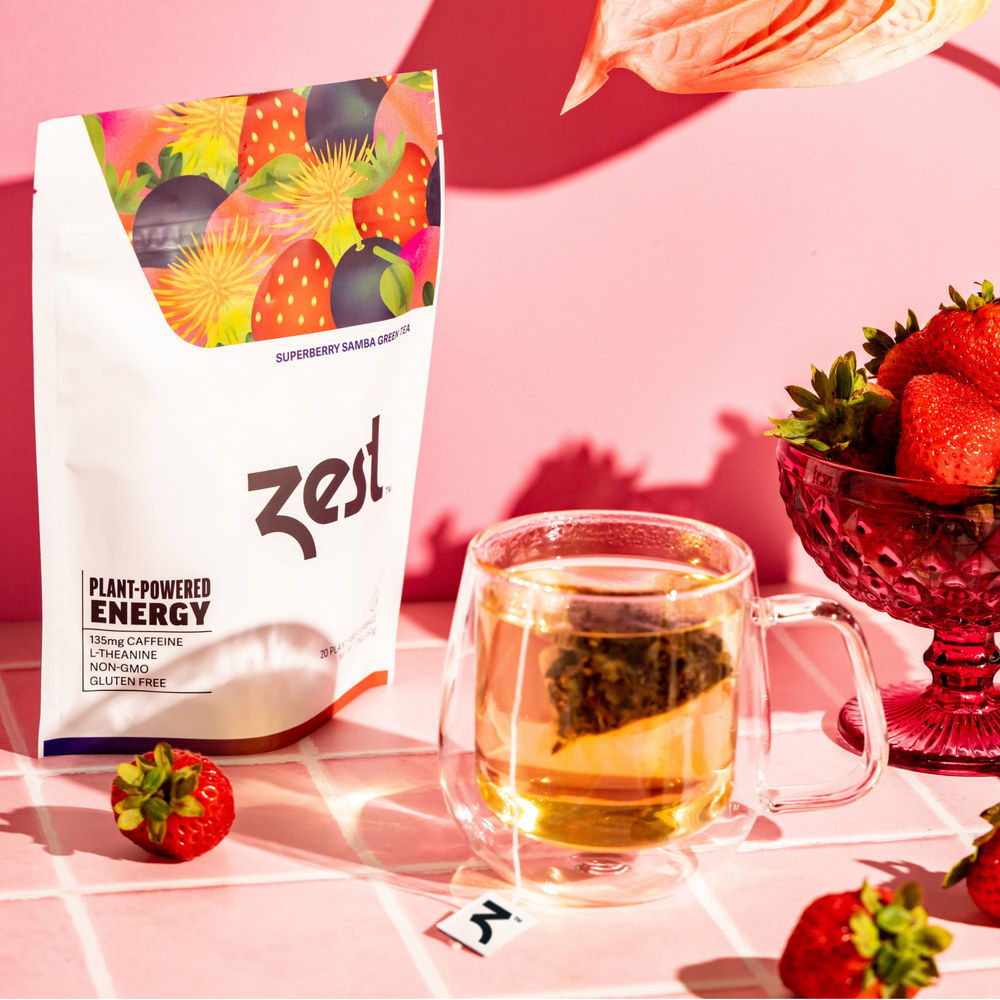 Zest Superberry Samba Loose Leaf pouch with brewed tea in glass mug and strawberries on pink tile